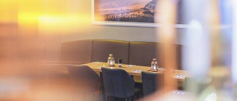 Un restaurante con una mesa dispuesta para dos, un cuadro de paisaje enmarcado en la pared y una iluminación ambiental cálida.