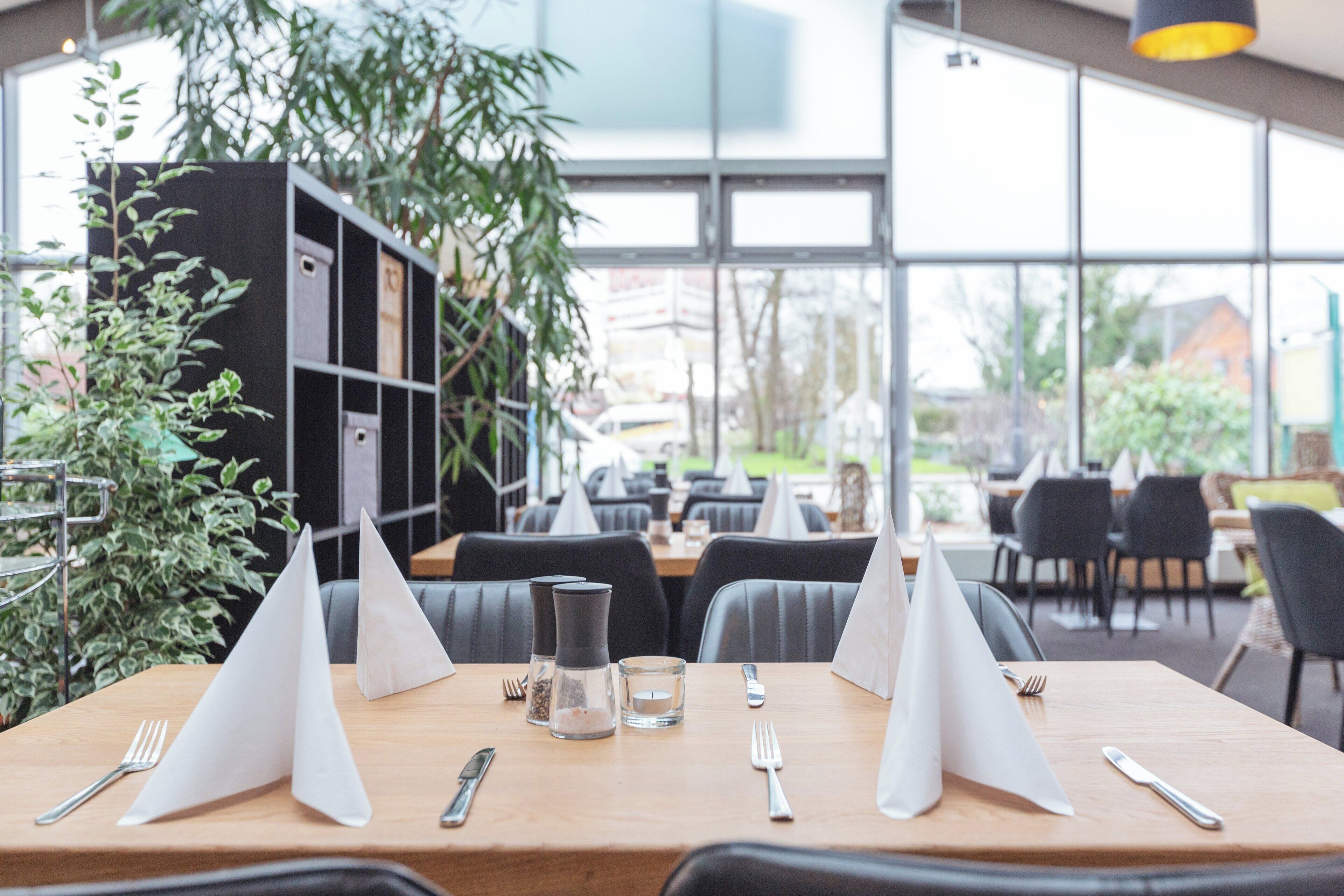 Ein Restaurant mit einem Holztisch, gedeckt für zwei Personen, inklusive Speisekarte, Wasserglas und Besteck.