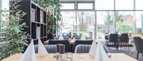 Un restaurante con una mesa de madera preparada para dos personas, incluyendo un menú, un vaso de agua y cubiertos.
