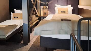 Ein Hotelzimmer mit zwei Betten, einem Nachttisch, einer Lampe und einer Treppe.