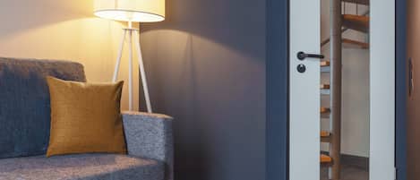 Una sala moderna con sofá, lámpara y puerta que da a una escalera.