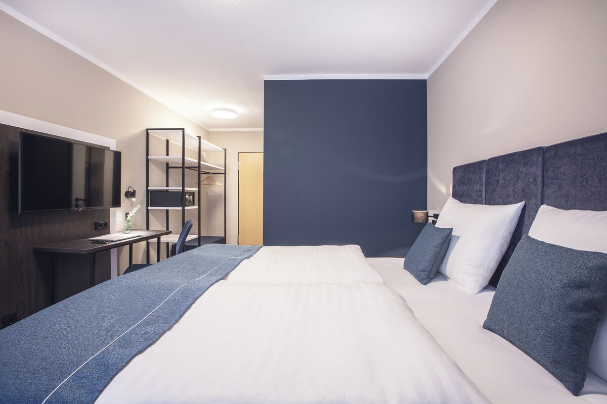 Une chambre d’hôtel moderne équipée d’un grand lit, d’un bureau, d’une chaise et d’un téléviseur.