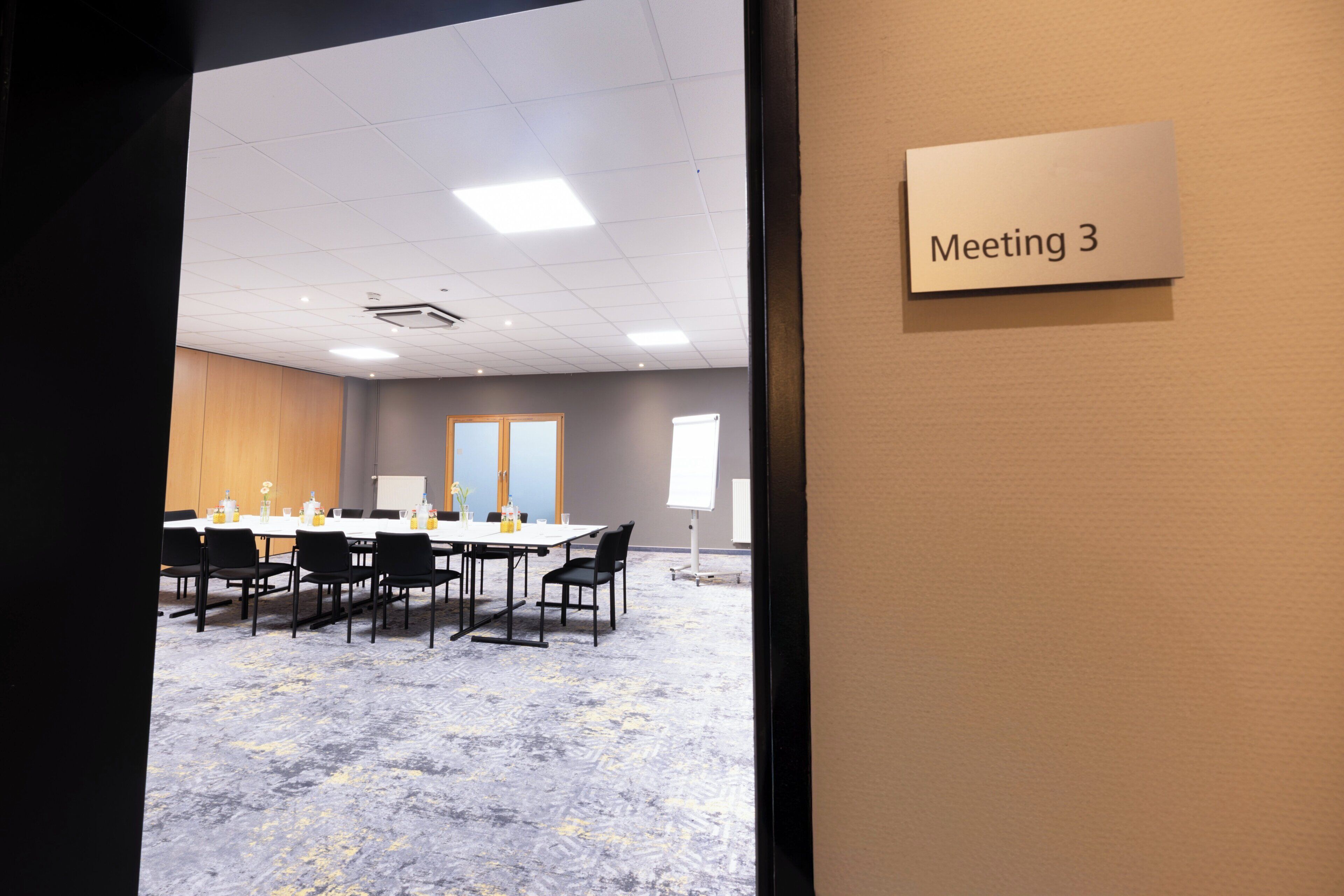 A conference room with a large table, chairs, and a 'Meeting 3' sign.