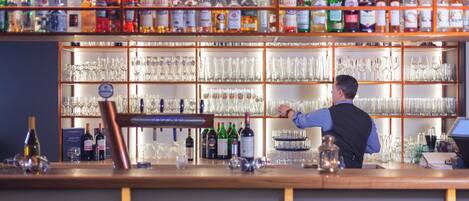 Un bar con estantes llenos de botellas de licor y vasos.