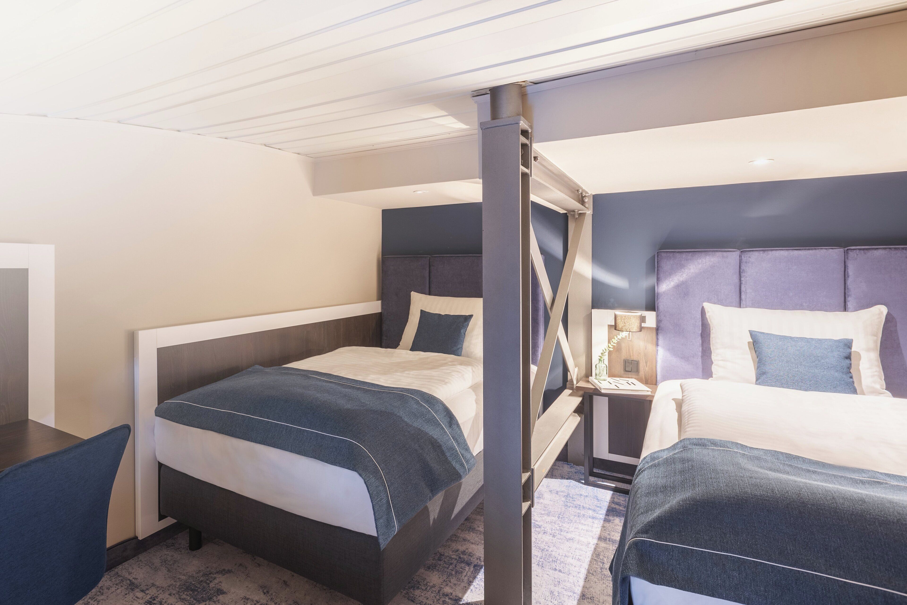 A hotel room with two beds, a desk, and a nightstand.