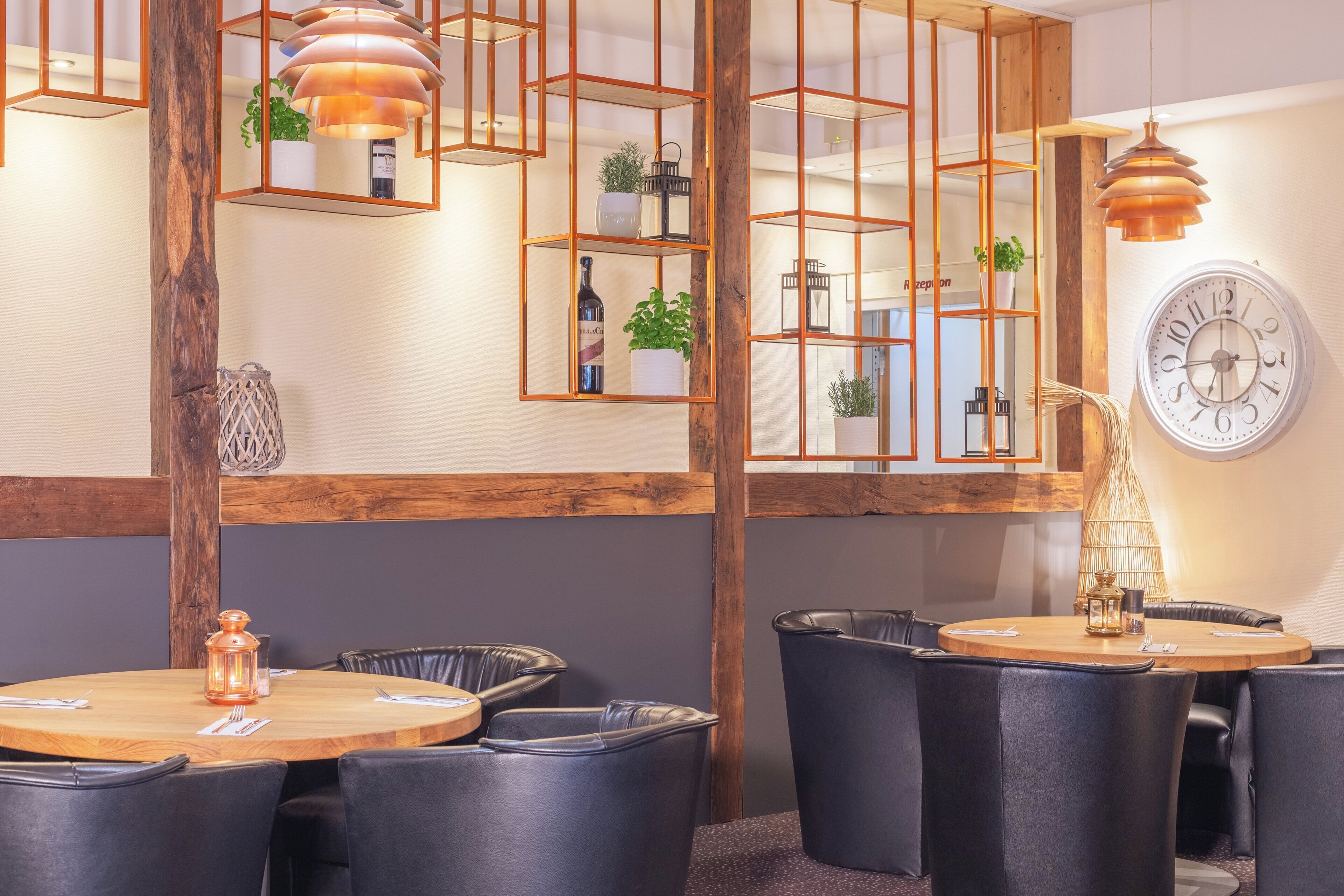 Un espace repas moderne avec des tables rondes, des chaises en cuir noir et des étagères aux motifs géométriques.