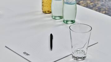 Un cuaderno con un bolígrafo y un vaso sobre una mesa.