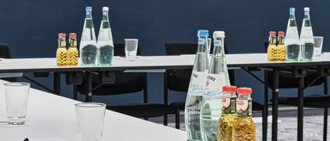 Un salón de conferencias con mesas dispuestas para una reunión, con botellas de agua, vasos y blocs de notas.