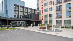 A modern hotel with a prominent 'THONHOTELS' sign, outdoor seating area, and a parking lot. - Thon Hotel Brønnøysund (Brønnøy)