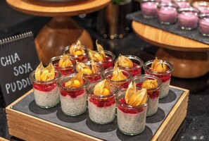 Eine Dessertpräsentation mit Chiasamen-Sojapudding in Gläsern, verziert mit Trockenfrüchten und einem goldenen Blatt.