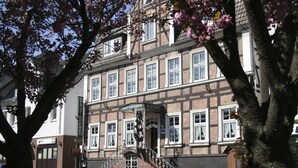 Een traditioneel Europees gebouw met een trap die naar de ingang leidt, een bord voor een restaurant en een zichtbare deur.