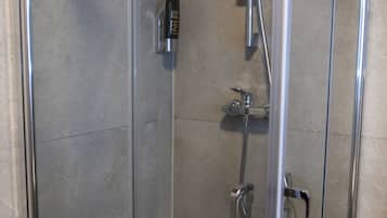 Un box de ducha con paredes de vidrio y tres cabezales de ducha manuales.