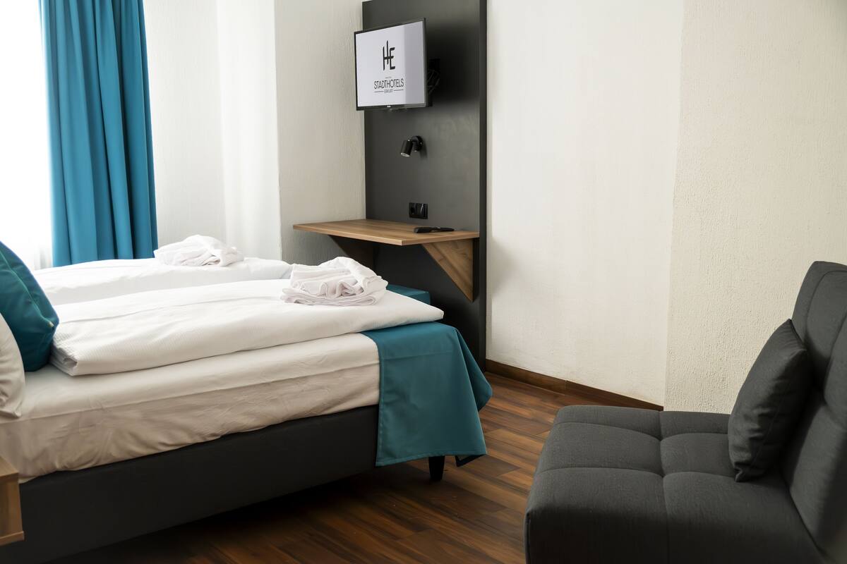 Una habitación de hotel con cama, escritorio, televisor y sofá.