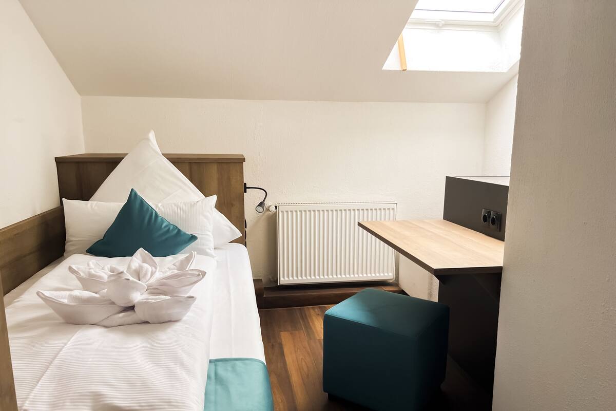 Una habitación pequeña con cama, escritorio y radiador.