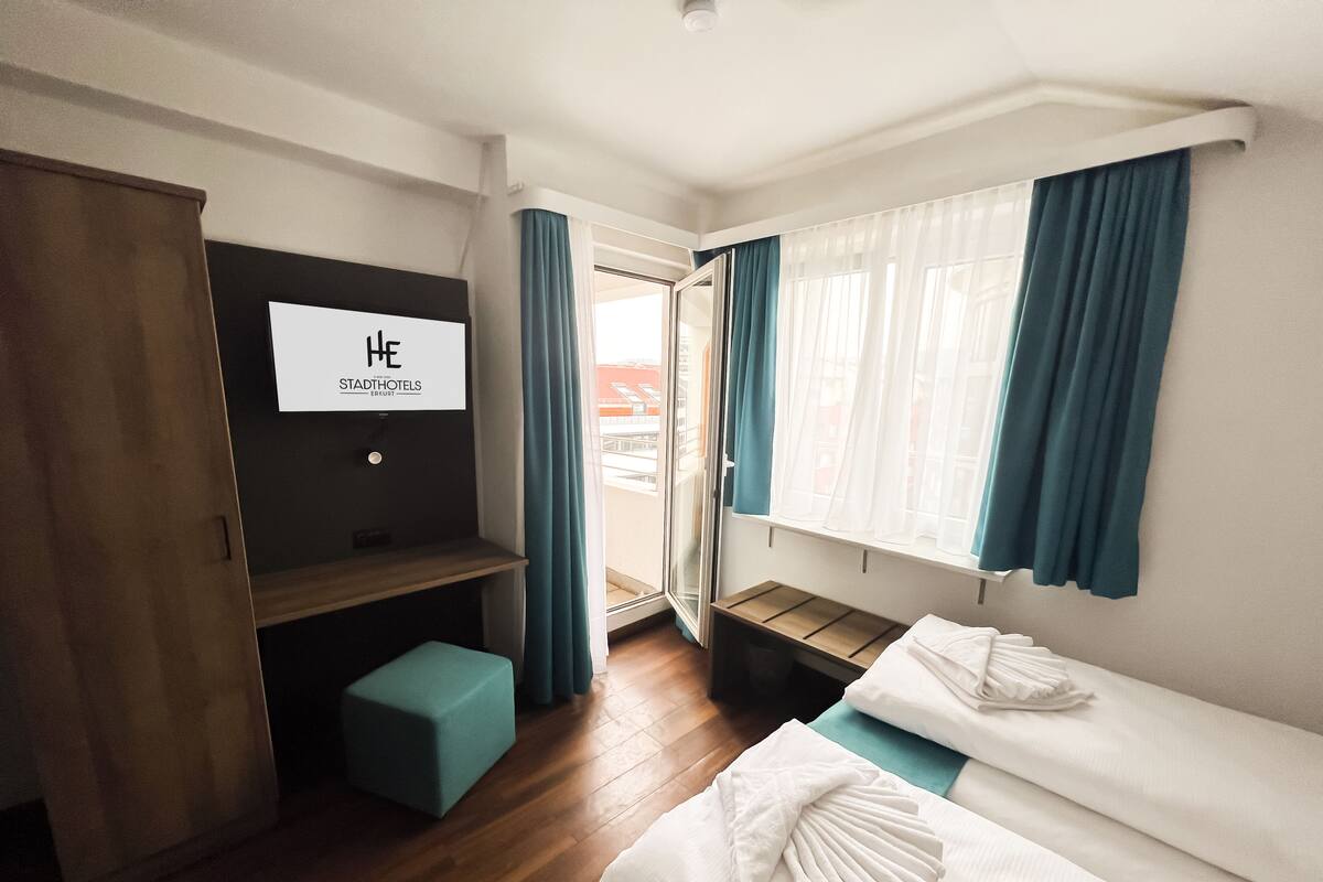 Una habitación de hotel con cama, un banco, un televisor y vistas al exterior.