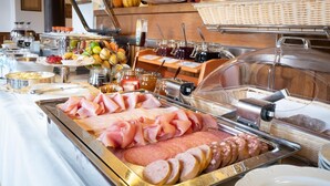 Een buffet met diverse vleessoorten, kazen en sausjes.