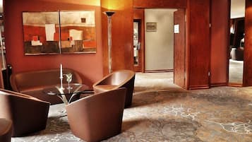 A modern lobby with a seating area, a floor lamp, and a patterned carpet.