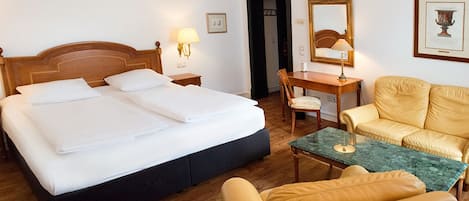 Ein Hotelzimmer mit einem großen Bett, einem Schreibtisch, einem Stuhl und einer Sitzecke.