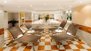 Een hotelbadkamer met zwart-wit betegelde vloer, meerdere wastafels en lounge fauteuils.