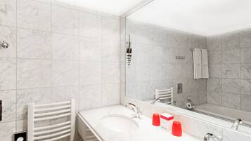 A modern bathroom with two sinks, a large mirror, and a towel rack.