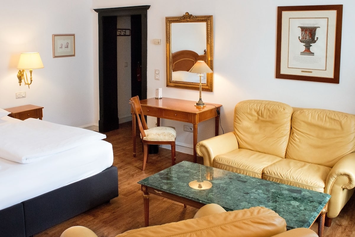 Une chambre d’hôtel comprenant un lit, un bureau, une chaise, un canapé et une petite table.
