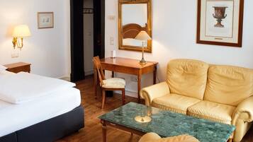 Una habitación de hotel con cama, escritorio, silla, sofá y una mesita.