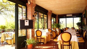 An outdoor dining area with brick pillars, yellow chairs, and tables set for dining.