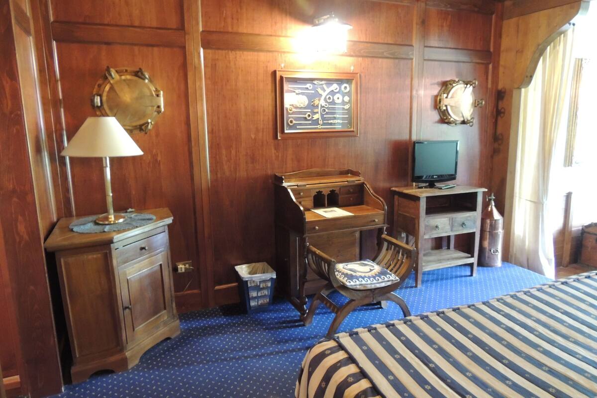 A wooden room with a bed, desk, chair, and a television.