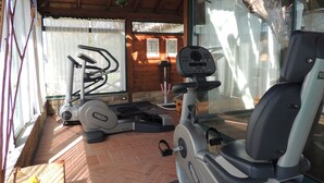 A covered outdoor gym area with exercise equipment, including a stationary bike and elliptical machine.