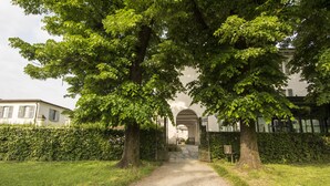 A pathway leading to a building with an arched entrance, surrounded by lush greenery and a hedge. - Hotel Parco Borromeo (Cesano Maderno)