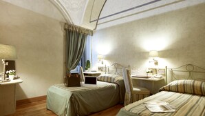 A hotel room with two single beds, a desk with a laptop, a small table with a lamp, and a nightstand with a lamp. - Hotel Parco Borromeo (Cesano Maderno)