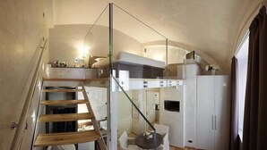 A compact, modern interior with a glass staircase, a loft bedroom, and a kitchenette. - Hotel Parco Borromeo (Cesano Maderno)
