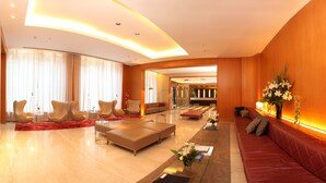 A spacious lobby with a red leather sofa, beige armchairs, and a marble floor. - 725 Continental (Buenos Aires)