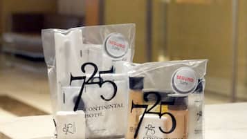 Three toiletries bags labeled 'Continental Hotel' with '75' and 'SEGUROSafe' branding, placed on a marble surface.