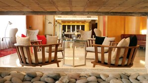 A modern lounge area with a glass-top table surrounded by wooden chairs with cushions. A chandelier hangs above the table, and a sign indicates social distancing measures. - 725 Continental (Buenos Aires)
