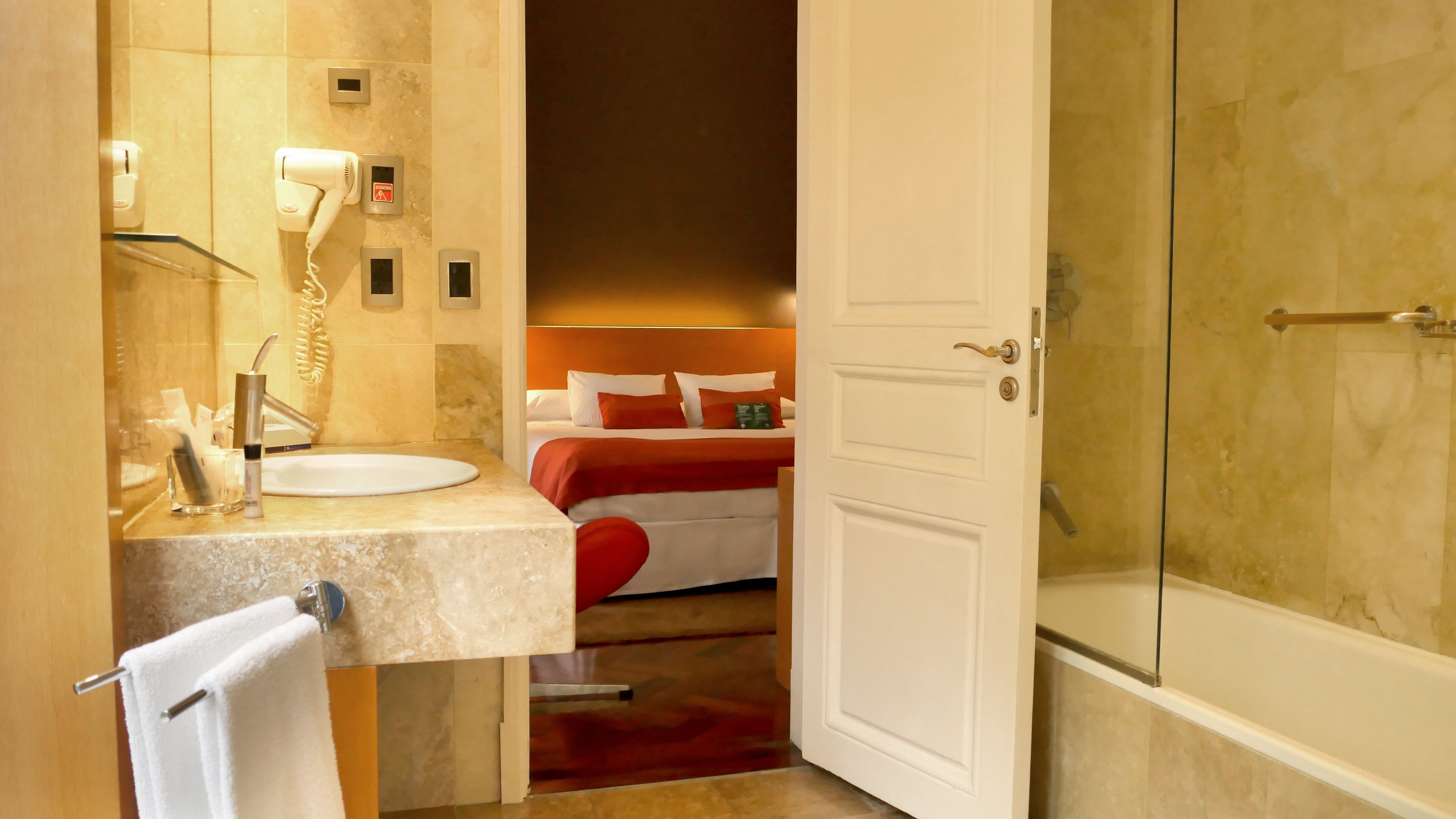 A hotel bathroom with a sink, mirror, and towel rack.