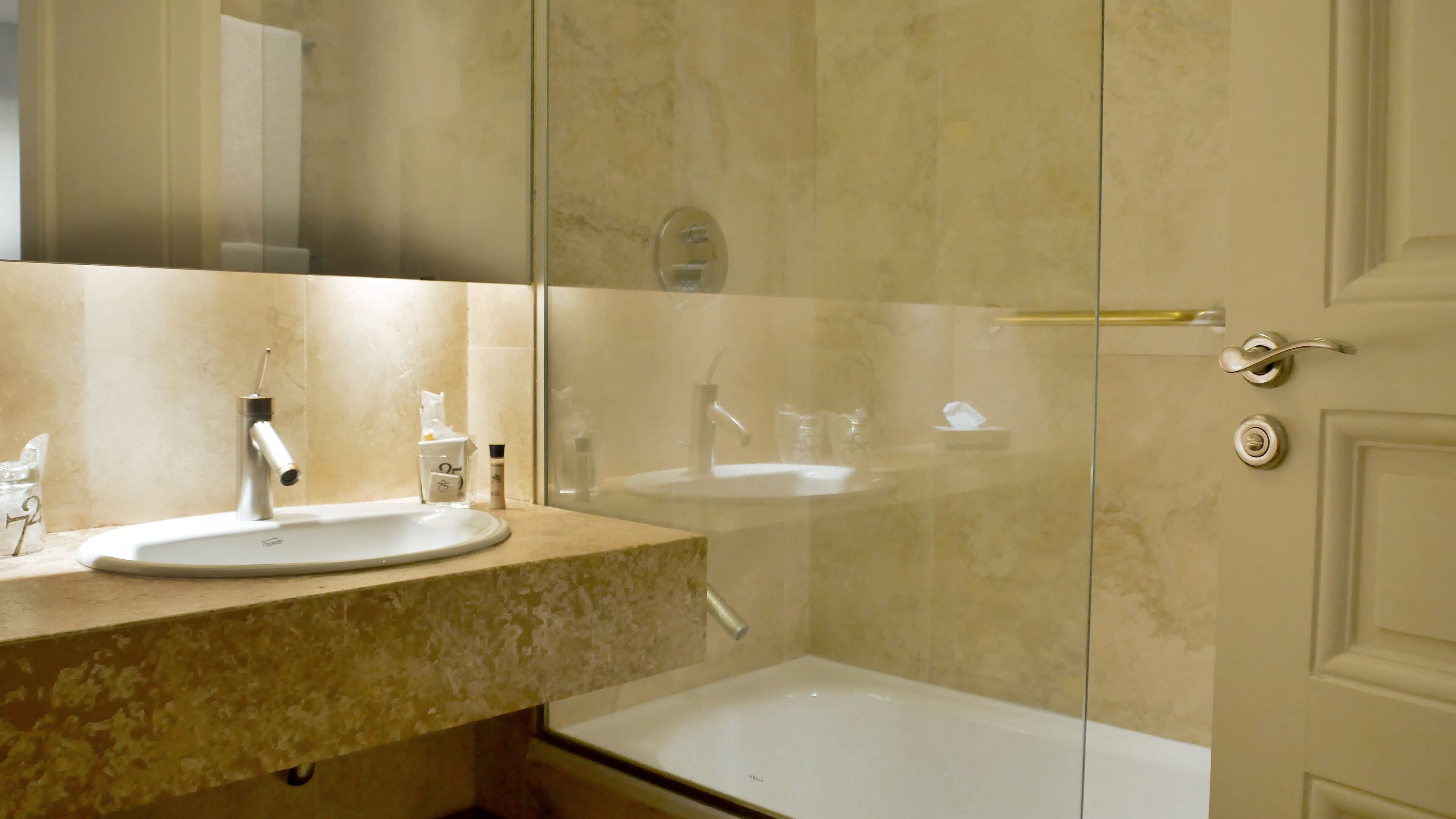 A bathroom with a sink, mirror, and shower.
