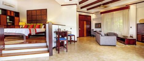 A spacious room with a bed, a desk, and a sofa. There is a staircase leading to another level.