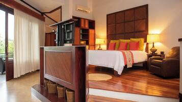 Habitación de hotel con cama, escritorio, silla, televisor y un ventanal con cortinas.