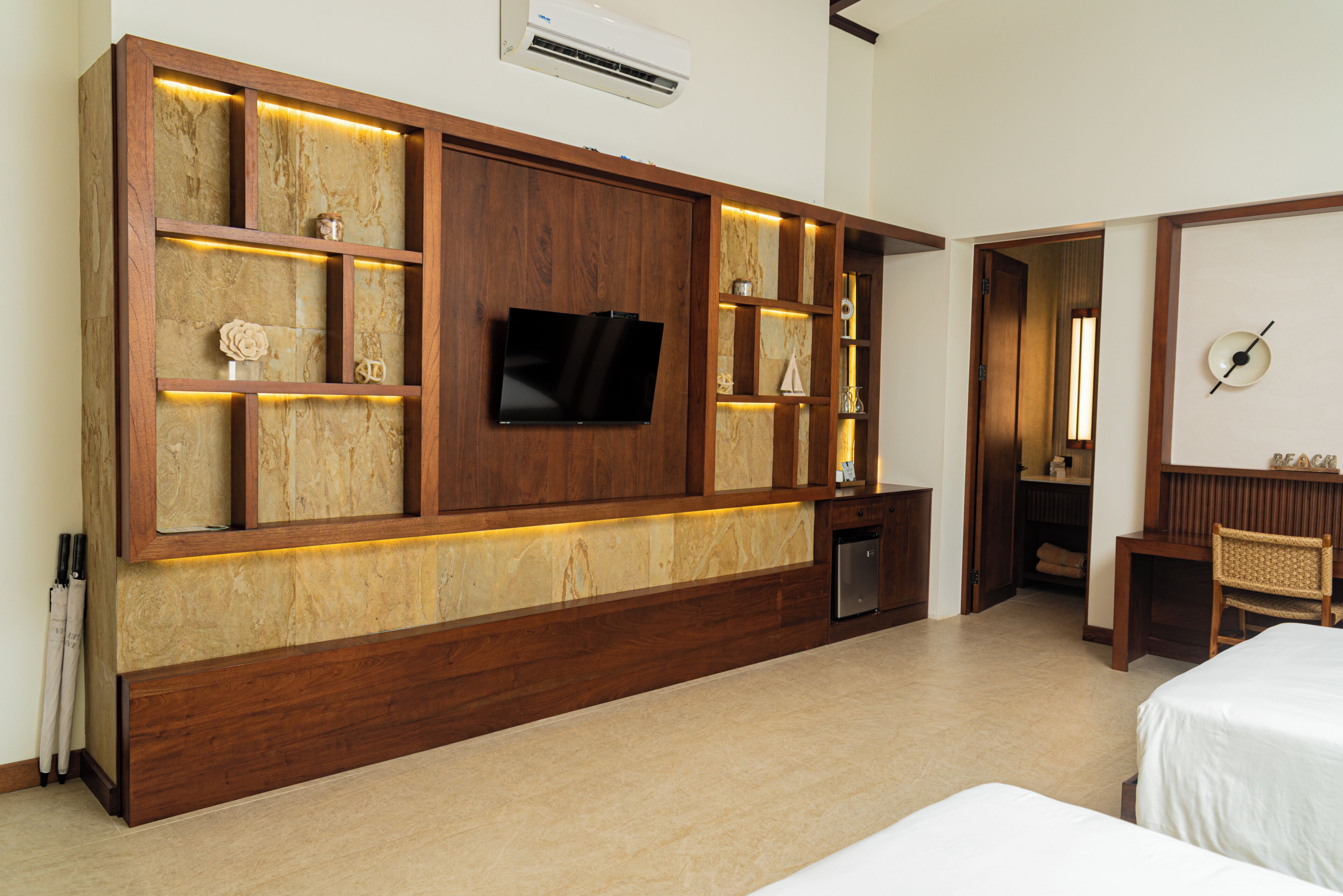 Habitación de hotel con un amplio mueble de madera, un televisor de pantalla plana, un escritorio pequeño y dos camas.