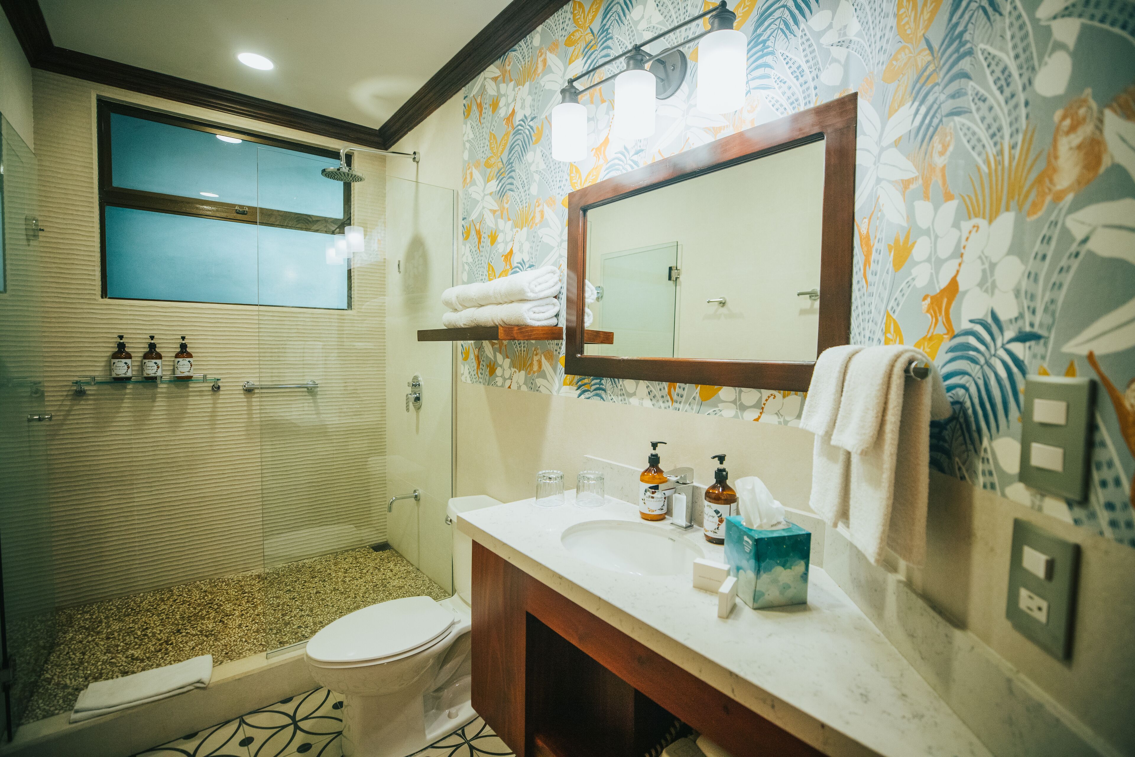 A bathroom with a shower, toilet, and sink. There are toiletries on the sink and a towel rack above it.