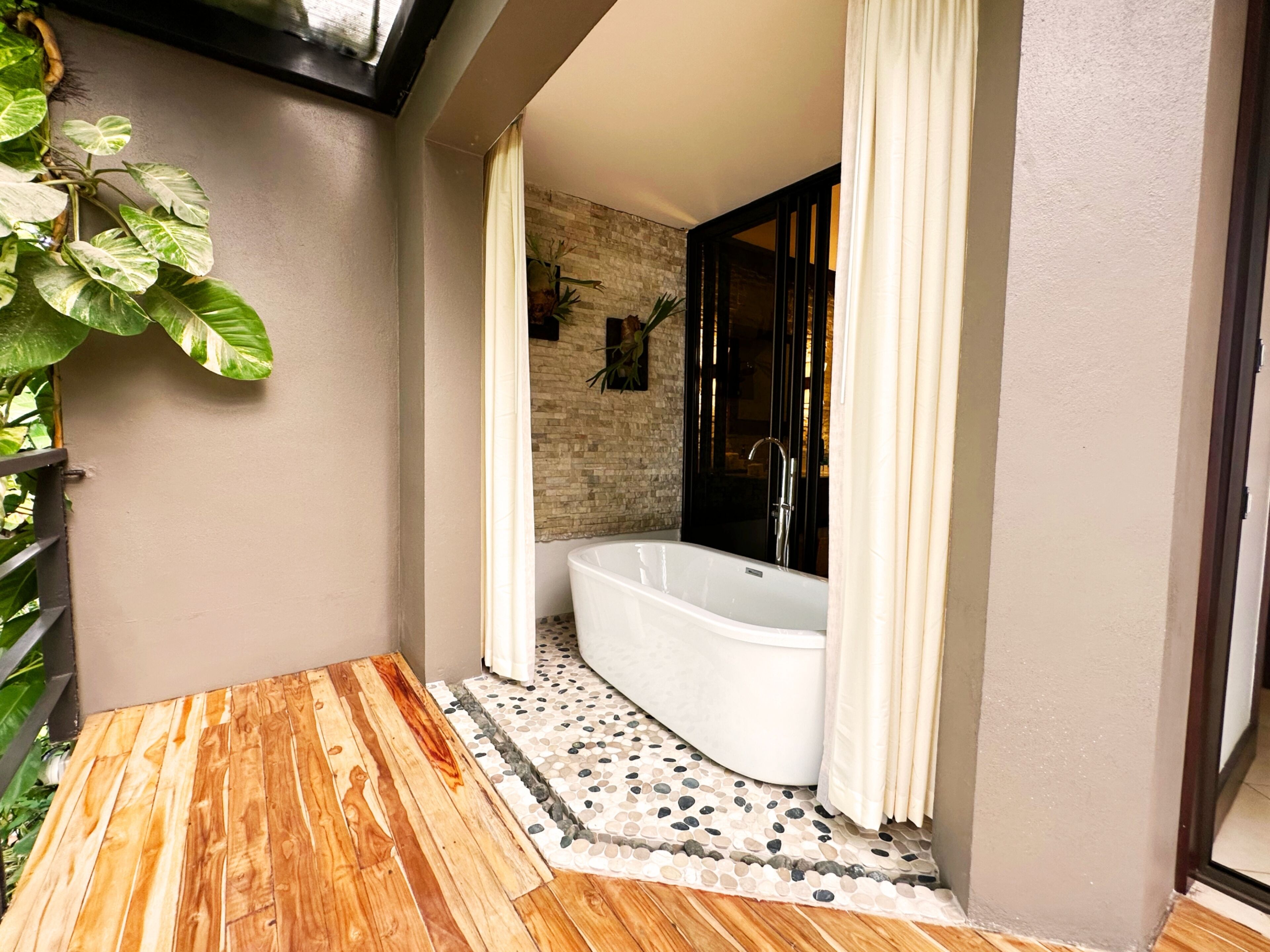 Un baño moderno con una bañera independiente, piso de mosaico y una zona de terraza de madera.