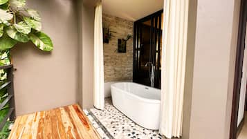 Un baño moderno con una bañera independiente, piso de mosaico y una zona de terraza de madera.