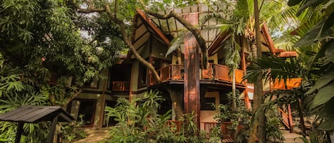 A tropical resort with a wooden structure surrounded by lush greenery and palm trees.