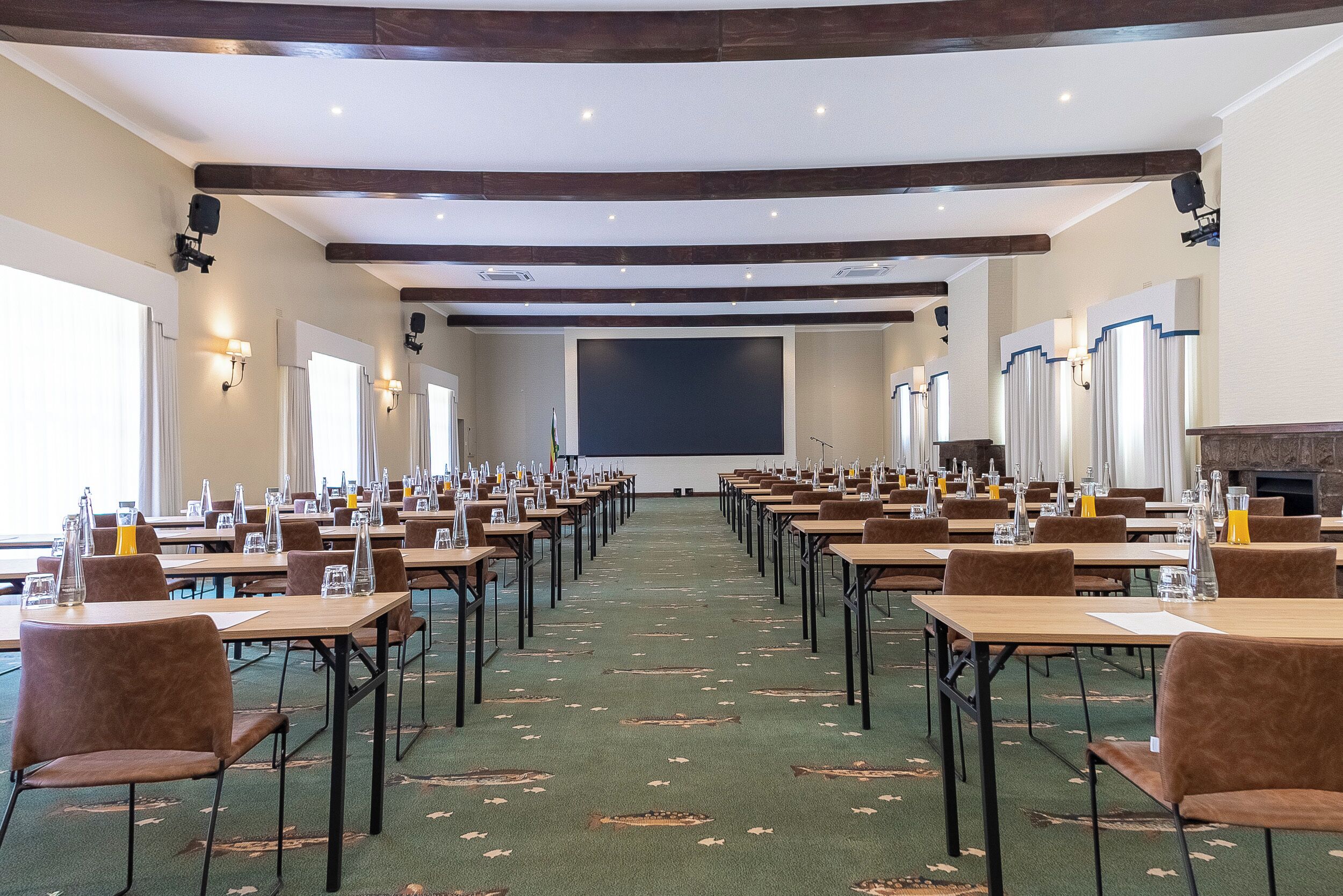 A conference room with tables and chairs, a projector screen, and a fireplace.