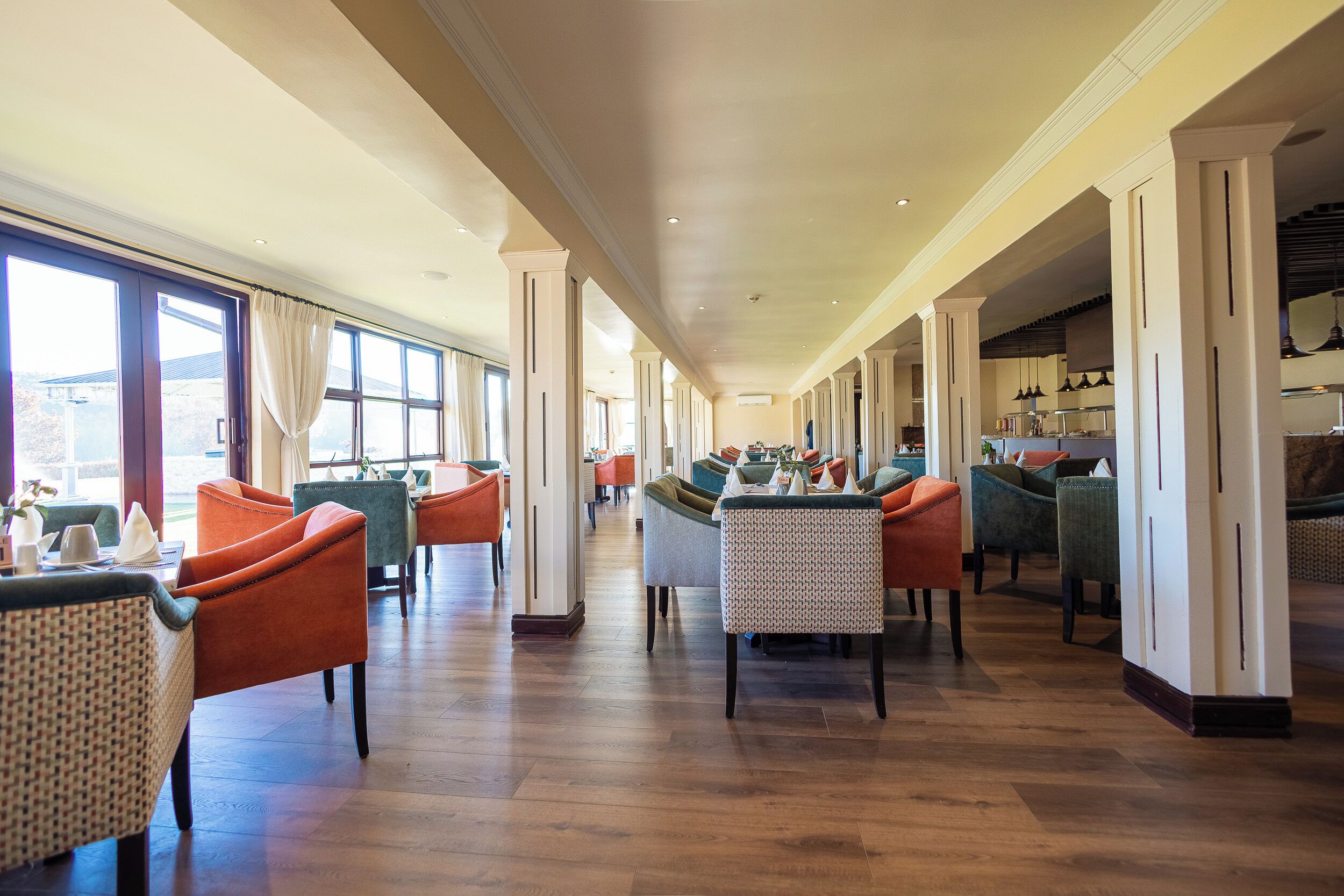 Eine geräumige Hotelhalle mit einem langen Korridor, mehreren Sitzbereichen und großen Fenstern.