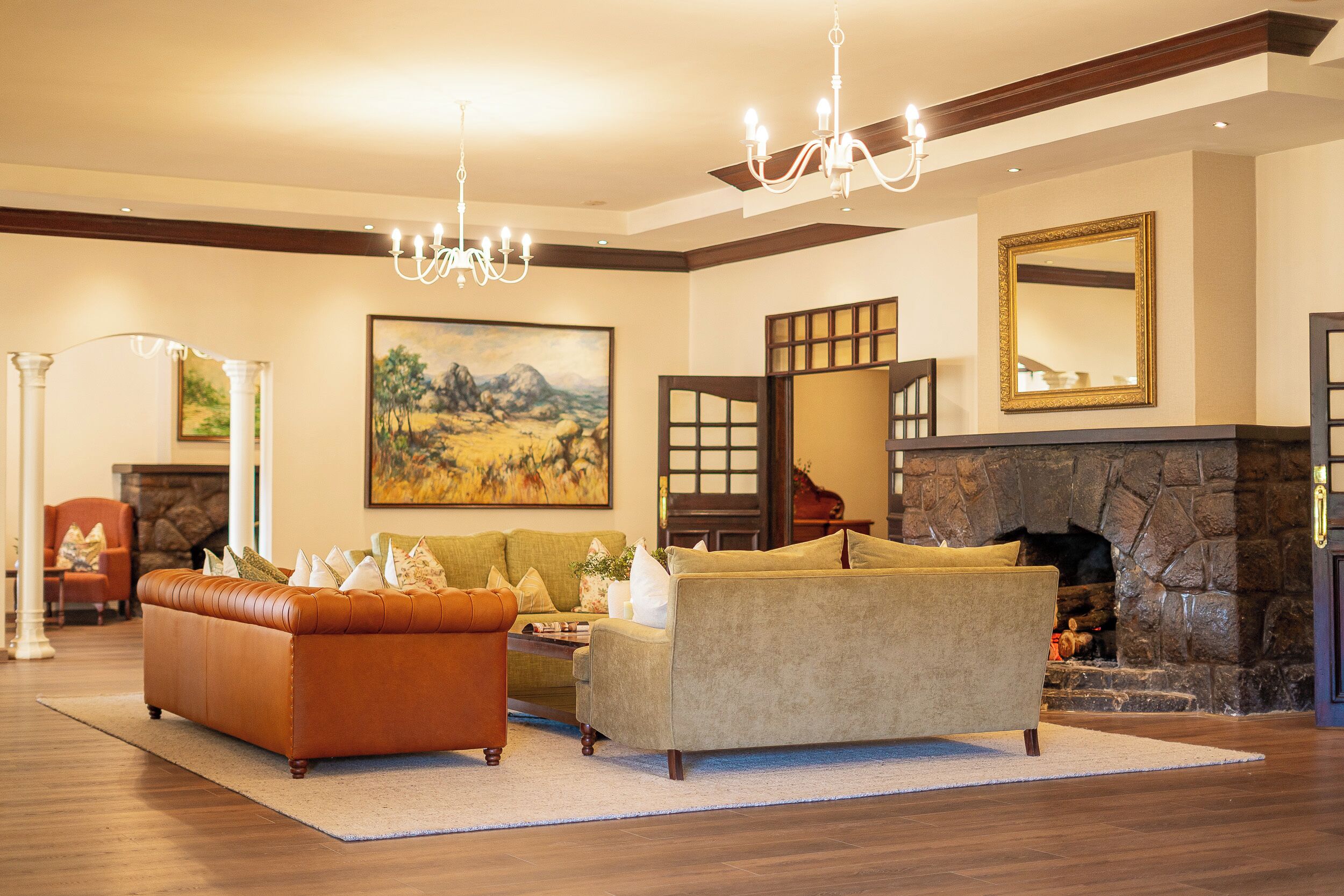A spacious living room with a fireplace, a large painting, and a chandelier.