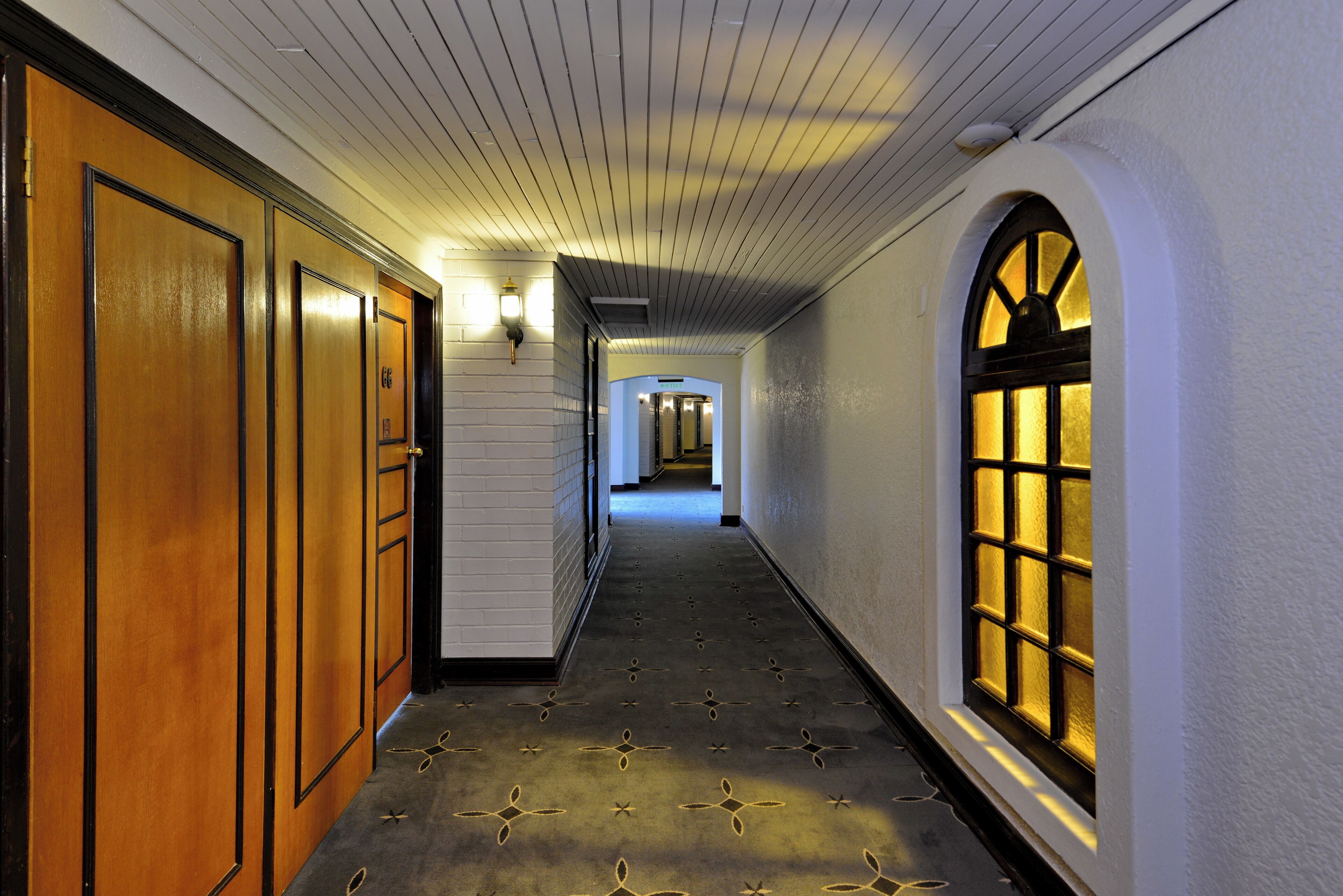 A hallway with wooden doors and a patterned carpet.