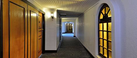 A hallway with wooden doors and a patterned carpet.