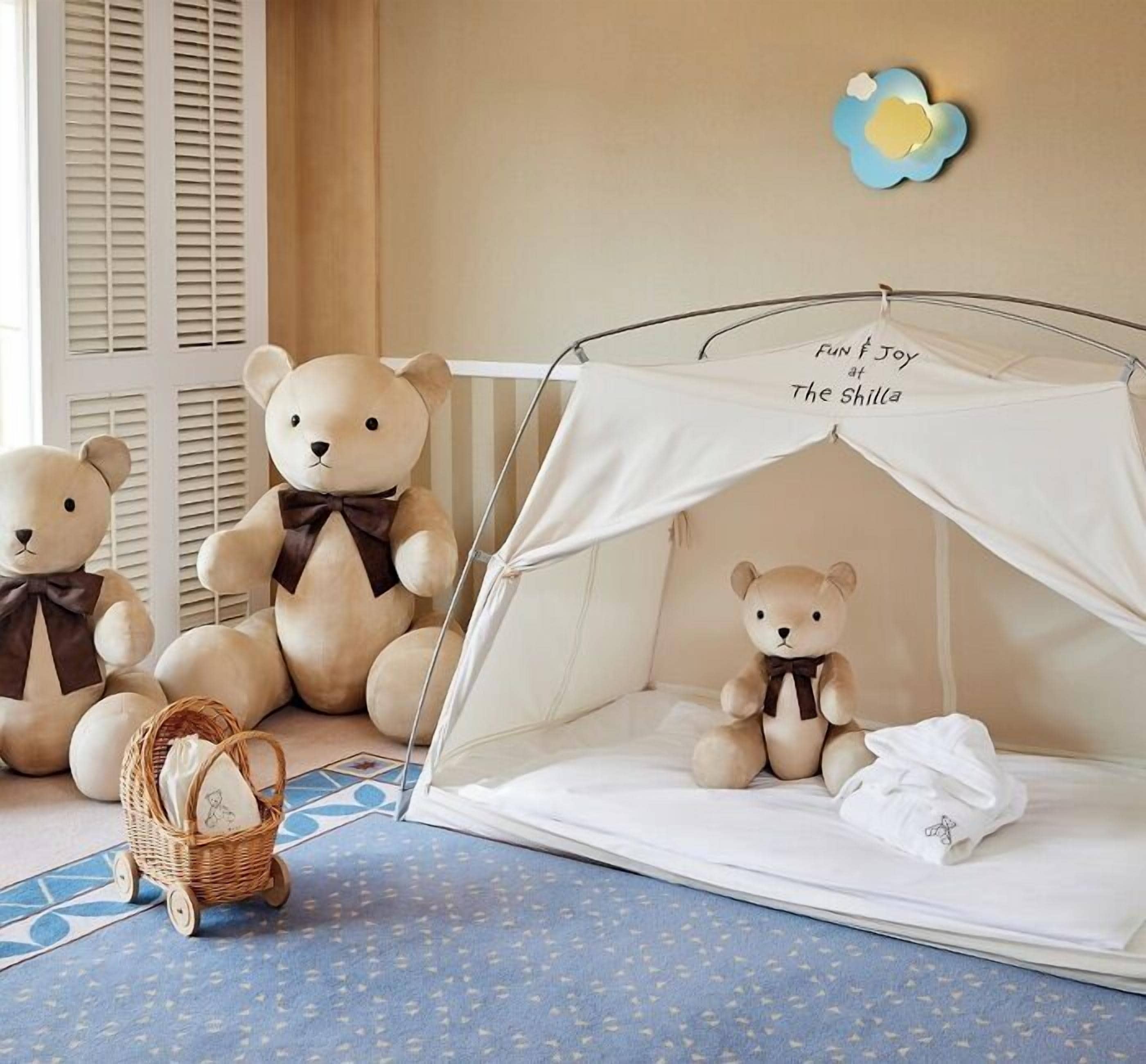 A room with a tent-like bed, two teddy bears, a basket, and a wall decoration.